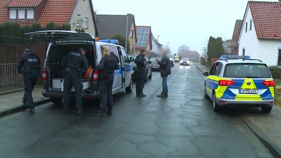 Polizeifahrzeuge und Einsatzkräfte der Polizei stehen in einer Wohnsiedlung.  