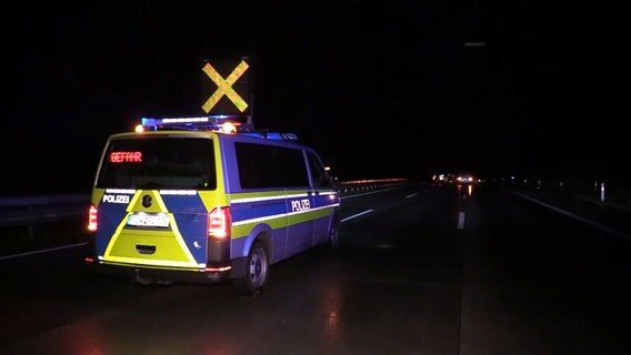 Ein Polizeiwagen sichert nachts eine Unfallstelle auf einer Autobahn.  