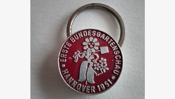 Ein Schlüsselanhänger mit dem Logo der Bundesgartenschau 1951 liegt auf einem Tisch. © NDR Foto: Werner  Heupke