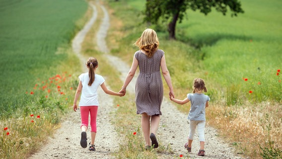 Eine Mutter und ihre beiden Töchter gehen einen Feldweg entlang. © dpa-Bildfunk Foto: Patrick Pleul/dpa-Zentralbild/dpa