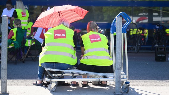 Beschäftigte im niedersächsischen Einzelhandel sitzen bei einem Warnstreik vor der Ikea-Filiale Expo-Park auf einem Einkaufswagen. © dpa/picture alliance Foto: Julian Stratenschulte