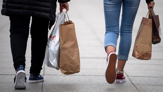Zwei Menschen gehen mit vollen Einkaufstaschen durch die Stadt. © picture alliance Foto: Monika Skolimowska