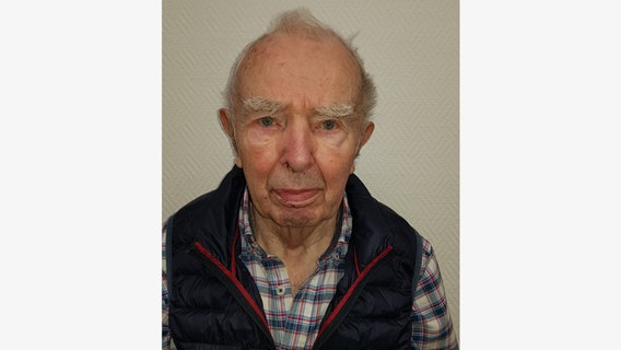 Ein 92 Jahre alter  Mann mit grauem Haar, einem rot-blauen Hemd und einer blauen Weste schaut in die Kamera. Es ist Ewald Behnemann und er wird vermisst. © Polizei Rotenburg 