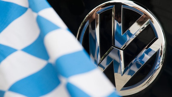 Eine Illustration zeigt eine blau-weiße Fahne und ein VW-Logo. © dpa - Bildfunk Foto: Peter Kneffel