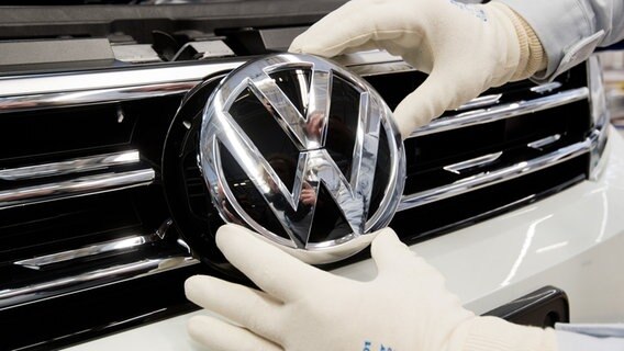 Ein Mitarbeiter montiert ein VW Logo an die Front eines VW Tiguan in der Endmontage im VW Werk in Wolfsburg. © dpa-Bildfunk Foto: Julian Stratenschulte