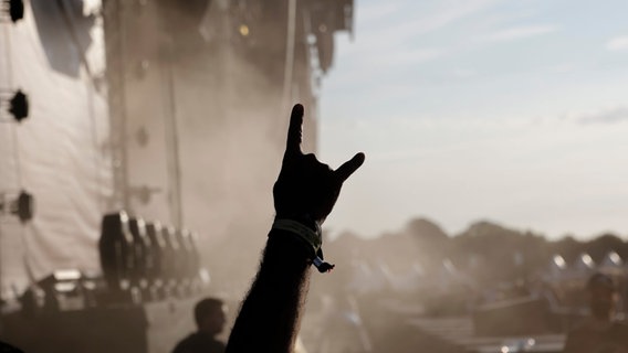 Ein Metal-Fan zeigt den Metal-Gruß während eines Auftritts der Band «Dirkschneider» beim Wacken Open Air (WOA). © picture alliance/dpa | Frank Molter Foto: Frank Molter