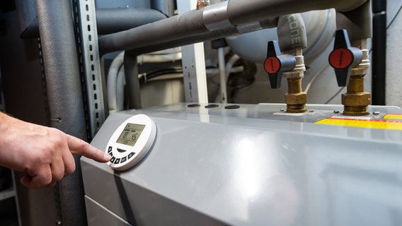 A man operates an air heat pump in the basement of a residential building.  © dpa-Bildfunk Photo: Silas Stein