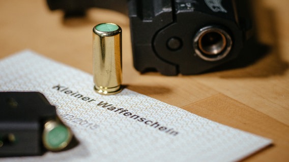 Ein kleiner Waffenschein liegt zwischen einer Schreckschuss-Pistole «Walther P22», einem Magazin und einer Platzpatrone. © dpa Foto: Oliver Killig