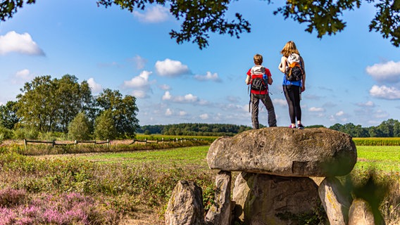 Zwei Wanderer stehen in der Steinalkenheide auf einem Grab. © Björn Wengler Fotografie Foto: Björn Wengler Fotografie