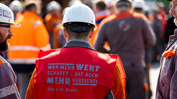 Beschäftigte der Salzgitter AG beteiligen sich an einem Warnstreik - der Schriftzug "Wer mehr Wert schafft - hat auch mehr verdient!" ist dabei auf einer Warnweste zu lesen. © picture alliance/dpa | Moritz Frankenberg 
