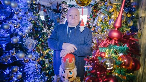 Thomas Jeromin steht zwischen Weihnachtsbäumen in seinem Haus. © picture alliance/dpa Foto: Ole Spata
