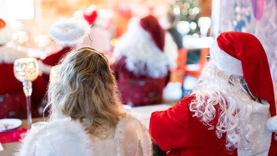 Zwei Teilnehmer einer Weihnachtsmann-Schulung sitzen während der Schulung als Weihnachtsengel und Weihnachtsmann verkleidet. © picture alliance/dpa/Michael Matthey Foto: Michael Matthey