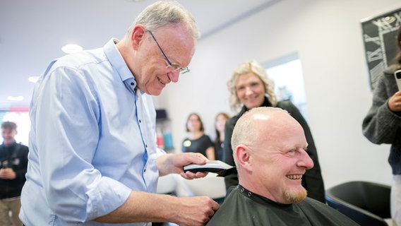 Stephan Weil (SPD), Niedersachsens Ministerpräsident, rasiert die Haare vom Kunden Stefan Dähne. © dpa-Bildfunk Foto: Sina Schuldt