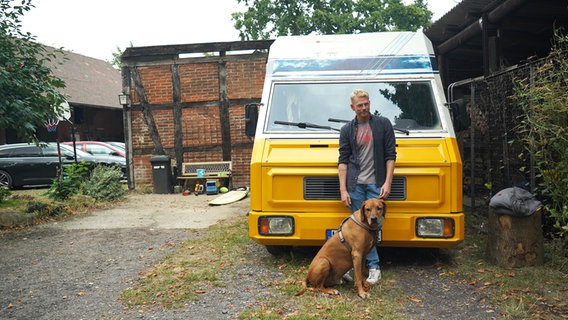 Stephan Krusch mit seinem Hund vor einem gelben Kleinbus. © NDR 