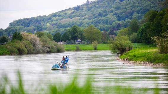 Eine Gruppe Stand-Up-Paddler aus Niedersachsen fährt auf einem großen Stand-Up-Board über die Weser im Landkreis Hameln-Pyrmont. Die Männer sind am Mittwoch in Hannoversch-Münden gestartet und wollen die Weser auf einer Länge von knapp 430 km bis nach Bremerhaven befahren – und das nonstop in 100 Stunden. © picture alliance/dpa Foto: Julian Stratenschulte