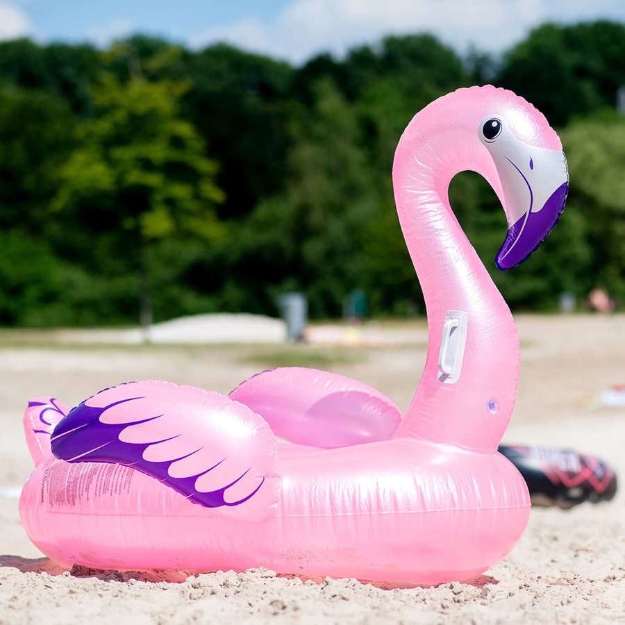 Ein aufblasbares Schwimmtier in Form eines Flamingos liegt bei sommerlichen Temperaturen im Sand an einem Badesee im Ortsteil Neermoor. © picture alliance Foto: Hauke-Christian Dittrich