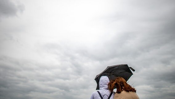 Zwei Frauen stehen unter einem Regenschirm und blicken auf dunkle Wolken. © picture alliance/dpa/Jonas Güttler Foto: Jonas Güttler