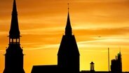 Die Silhouetten der Kreuzkirche und Marktkirche von Hannover vor einem Sonnenaufgang. © dpa-Bildfunk Foto: Julian Stratenschulte