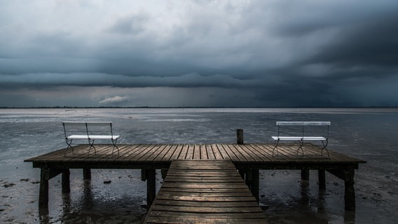 Steg und Bänke am Dangaster Strand mit dramatischen Wolken. © NDR Foto: Sascha Meinardus