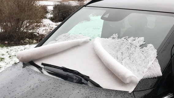 Auf der Windschutzscheibe eines Autos liegt Schnee in ungewöhnlicher Form. © NDR Foto: Jörg Baum