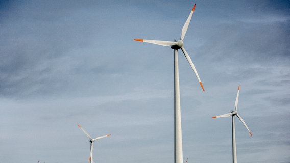 Drei Windräder stehen unter leicht bewölktem Himmel. © NDR Foto: Julius Matuschik