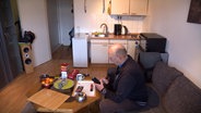 Ein Mann sitzt in einer Einzimmerwohnung. © NDR 