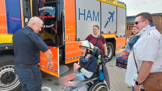 Feuerwehrmann Thomas Barke schenkt dem 17-jährigen Piet Werner einen echten Feuerwehrhelm. © NDR Foto: Maximilian Seib