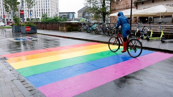 Eine Fahrradfahrerin radelt über einen Zebrastreifen in Regenbogenfarben. © picture alliance/dpa Foto: Daniel Löb