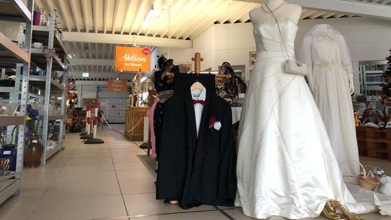 Im Eingangsbereich eines Second-Hand-Ladens steht eine Hochzeitstafel. © NDR Foto: Julia Barthel