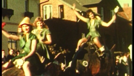 Drei Frauen sitzen auf Nachbildungen großer Karpfen und fahren auf einem Festwagen über ein Karpfenfest in den 1950er Jahren in Reinfeld.  