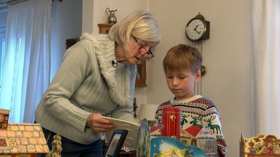 Adventskalender-Sammlerin Angelika Salzwedel zeigt ihrem Enkel einen alten Adventskalender aus ihrer Sammlung. © NDR 