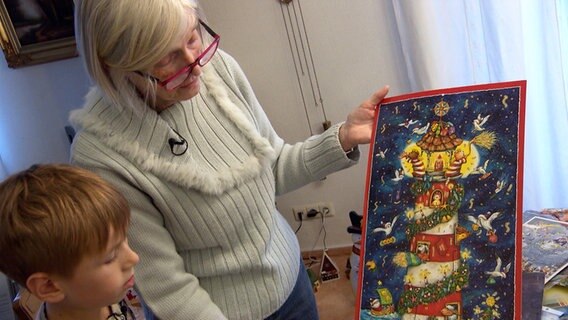 Adventskalender-Sammlerin Angelika Salzwedel zeigt ihrem Enkel einen alten Adventskalender aus ihrer Sammlung. © NDR 
