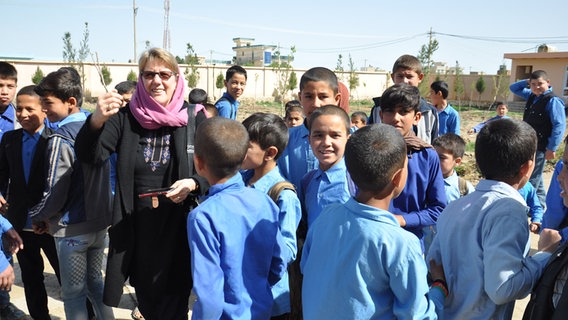 Eine Frau blickt in die Kamera und ist umgeben von afghanischen Schülern.  Foto: Marga Flader
