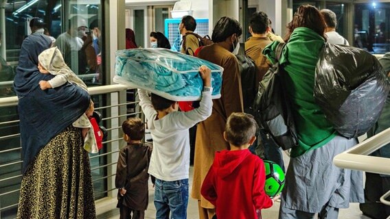 Evakuierte Flüchtlinge aus Kabul stehen im Flughafen der US Air-Base in Ramstein in Miesenbach. © picture alliance / ZUMAPRESS.com | Airman Edgar Grimaldo/U.S. Air 