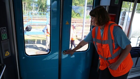 Eine Bahn-Mitarbeiterin drückt den Knopf zur Türöffnung. © NDR Foto: Ole Wrobel