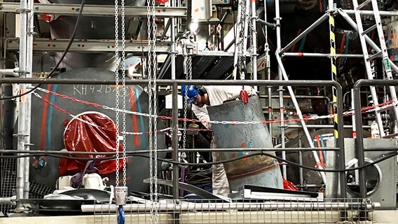 Ein Mann in Schutzkleidung rollt ein Metallfass. © NDR Foto: Marlene Santel