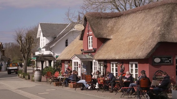 Amrum: Gäste sitzen vor einem Restaurant in der Sonne. © NDR 