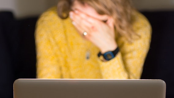 Eine Frau sitzt vor einem Laptop und hält sich die Hand vor die Augen. © dpa/picture alliance Foto: Dominic Lipinski