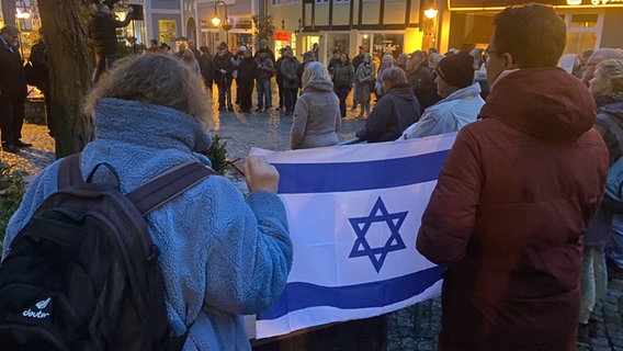 Two people hold the flag of Israel in the air during a demonstration.  © NDR Photo: Fabian Boerger