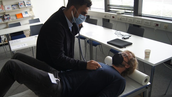 Ein Mann hört eine liegnede Person ab, mit einem Stethoskop. Ein Mann hört eine liegnede Person ab, mit einem Stethoskop. © NDR Foto: Astrid Wulf