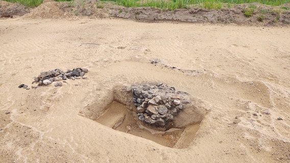 An der Seite eines Grabungsschachtes türmen sich viele Steine. © NDR Foto: Peer-Axel Kroeske