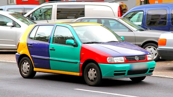 Ein bunter VW Polo fährt durch eine Stadt. © IMAGO / Dreamstime 