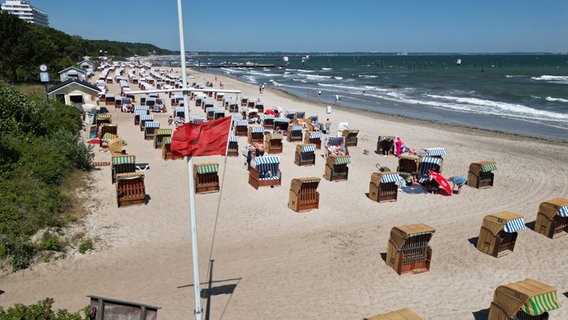 Die rote Flagge wurde an einem Badestrand gehisst, am Strand stehen viele Strandkörbe. © NDR Foto: Tobias Gellert