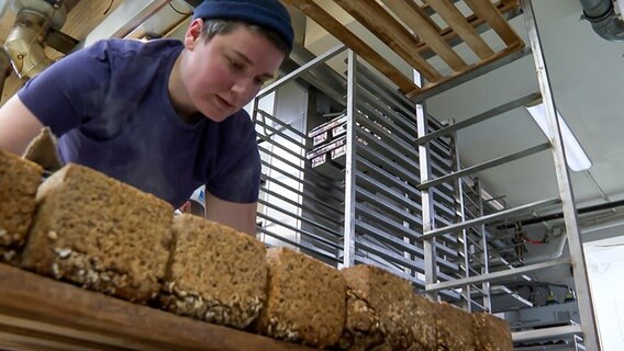 Bäckerin Jana Klausberger bückt sich über frisch gebackene Brote in ihrer Bäckerei in Eutin. © NDR 