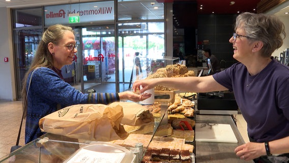 Eine Kundin bekommt Rückgeld von einer Verkäuferin in der Bäckerei Klausberger in Eutin. © NDR 