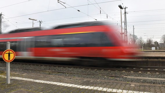 Eine Regionalbahn der Deutschen Bahn fährt mit rasanten Tempo an einem Warn- und Verbotsschild vorbei . © imago images Foto: Jan Huebner