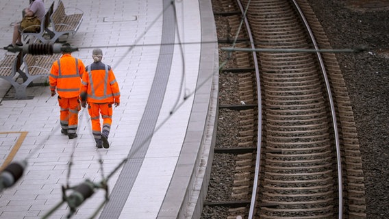 Zwei Bauarbeiter laufen einen Bahnsteig entlang. © Imago Images / Arnulf Hettrich Foto: Arnulf Hettrich