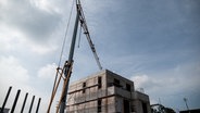 Der unfertige Rohbau eines Neubauhauses mit Gerüst und Kran. © imago images / Funke Foto Foto: Funke Foto