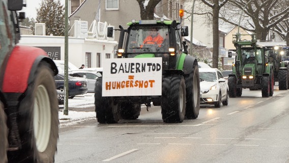 Ein Traktor fährt auf einer Straße, an ihm ist ein Schild montiert, auf diesem Steht: "Bauerntod = Hungersnot" © Daniel Friederichs Foto: Daniel Friederichs