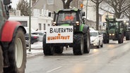 Ein Traktor fährt auf einer Straße, an ihm ist ein Schild montiert, auf diesem Steht: "Bauerntod = Hungersnot" © Daniel Friederichs Foto: Daniel Friederichs